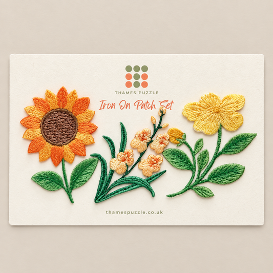 Thames Puzzle Iron On Patch Set featuring embroidered flowers on a cream card, including a sunflower, green leaves, and small peach blossoms, photographed on a neutral beige background.